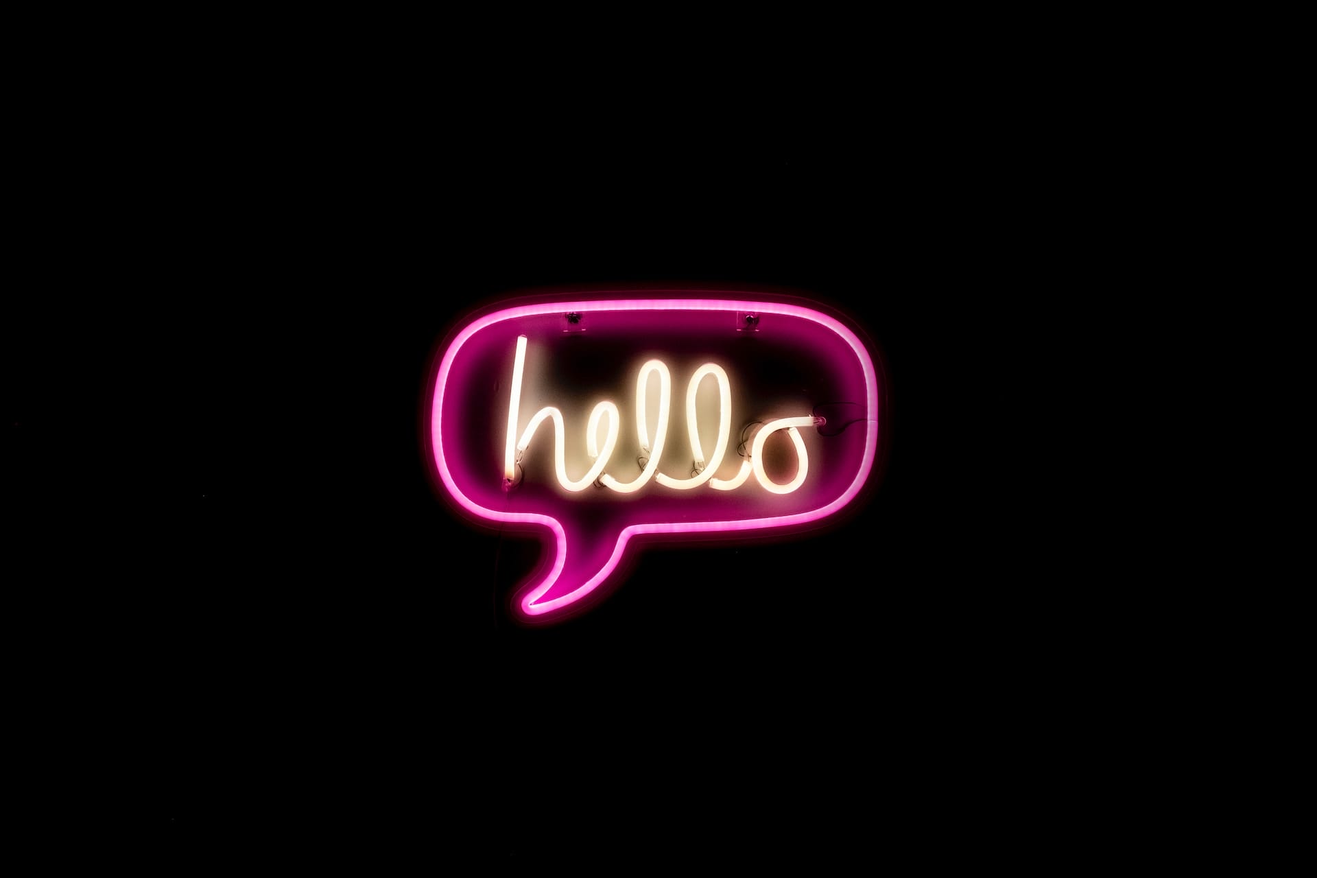 Neon sign with the word 'hello' against dark background.
